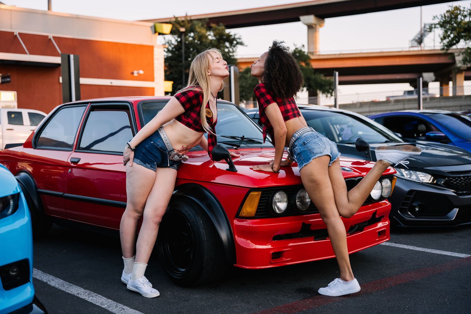 Modified red BMW E30 on display at an outdoor car meet.
