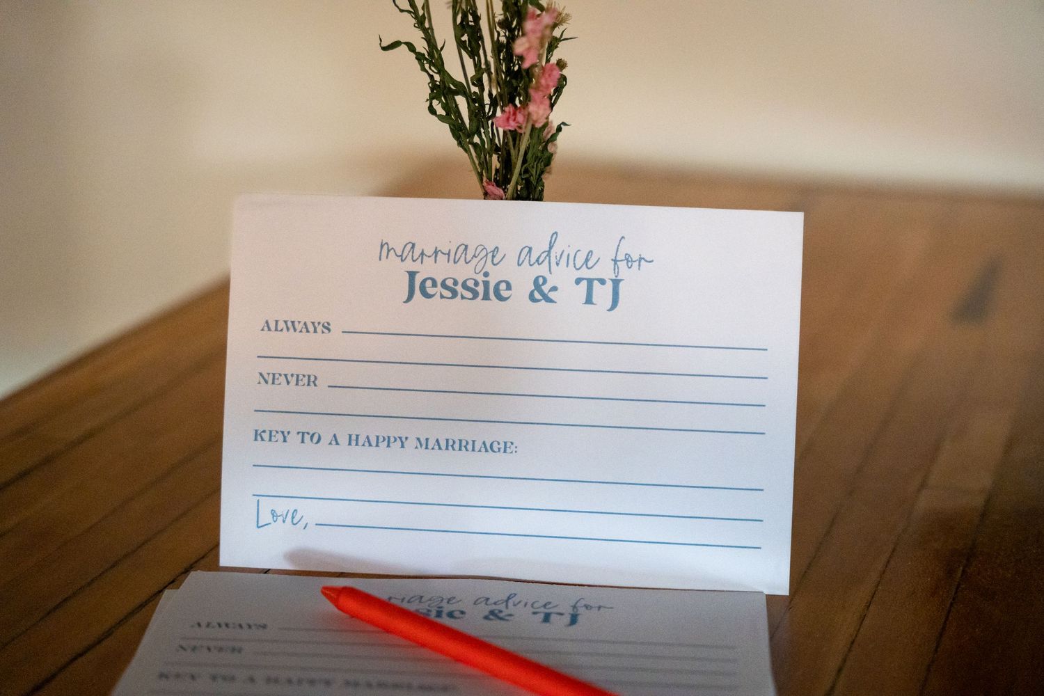 Marriage advice card for Jessie and TJ with red pen on wooden table.
