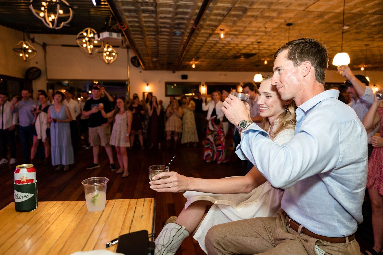 Guests enjoying themselves at a dimly lit indoor social gathering.