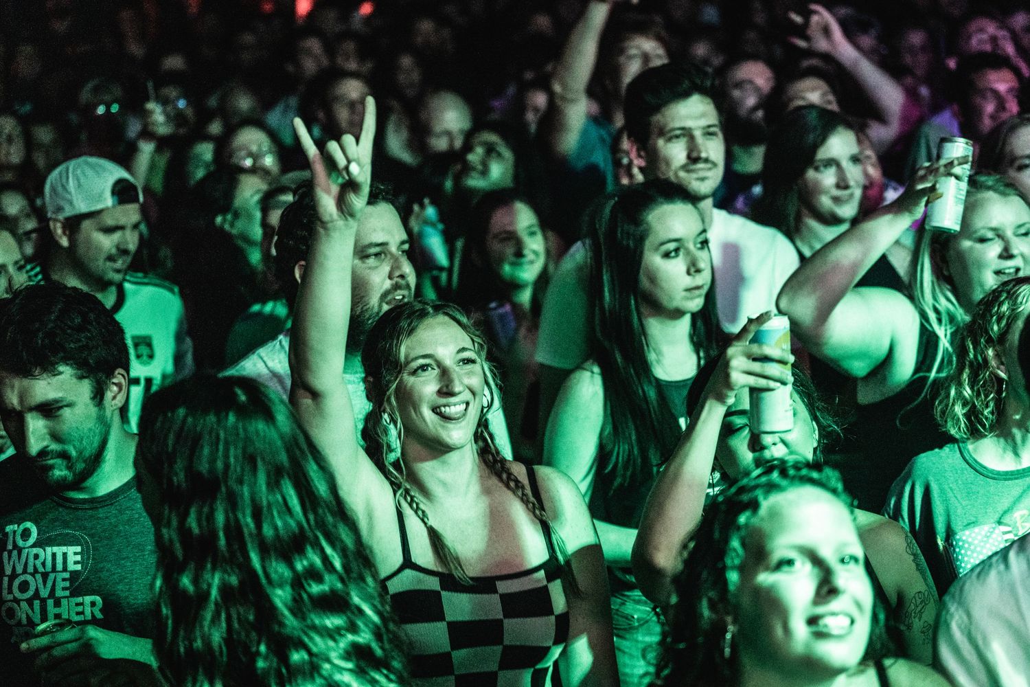 Excited crowd reacts during live music performance with atmospheric lighting.