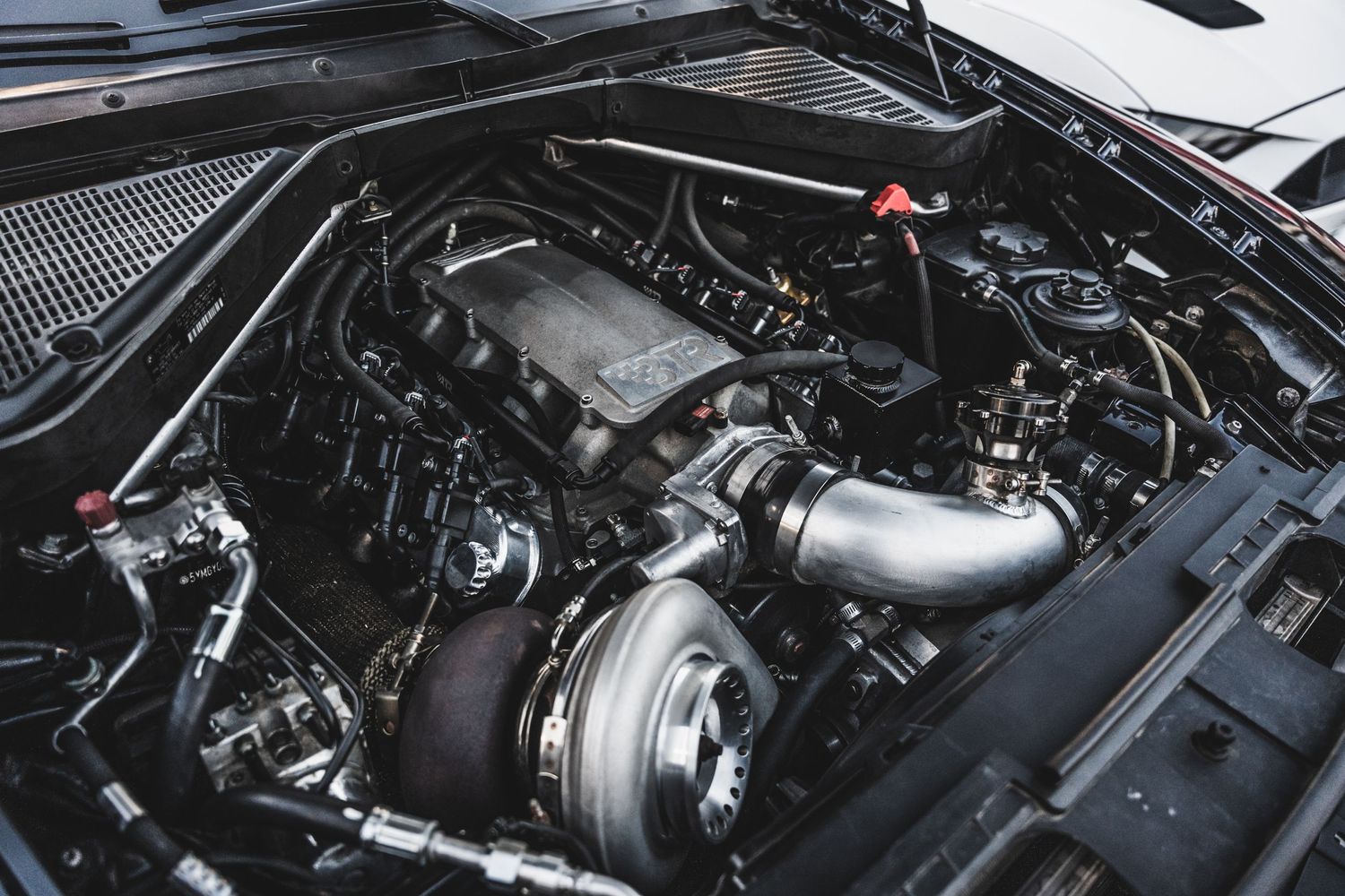 Modified engine bay showing performance parts and turbocharger setup.