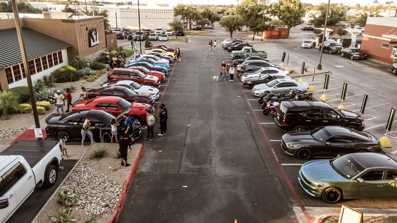 Birds eye view of cars parked in rows at a shopping center parking lot.