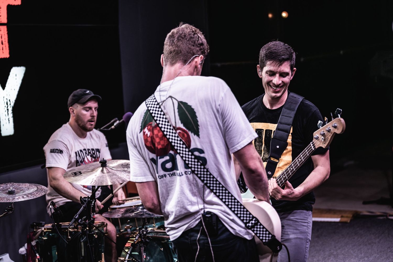 Band members playing instruments and interacting during a live performance on stage.