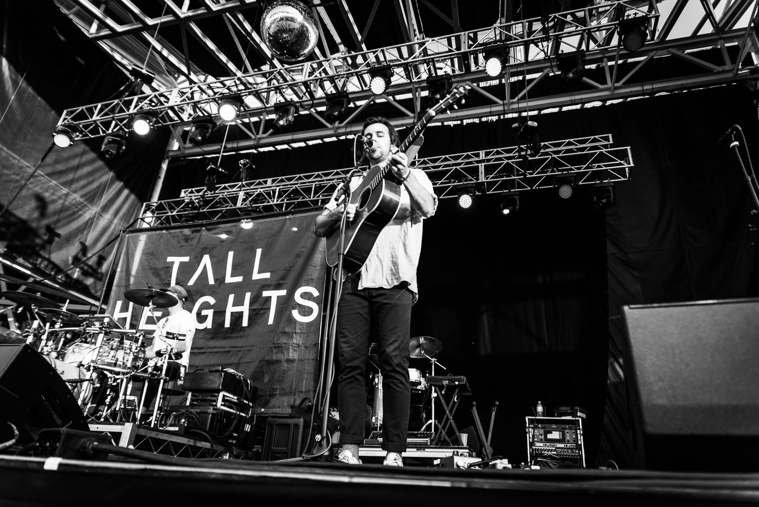 Black and white photo of performer on stage with Tall Lights backdrop.
