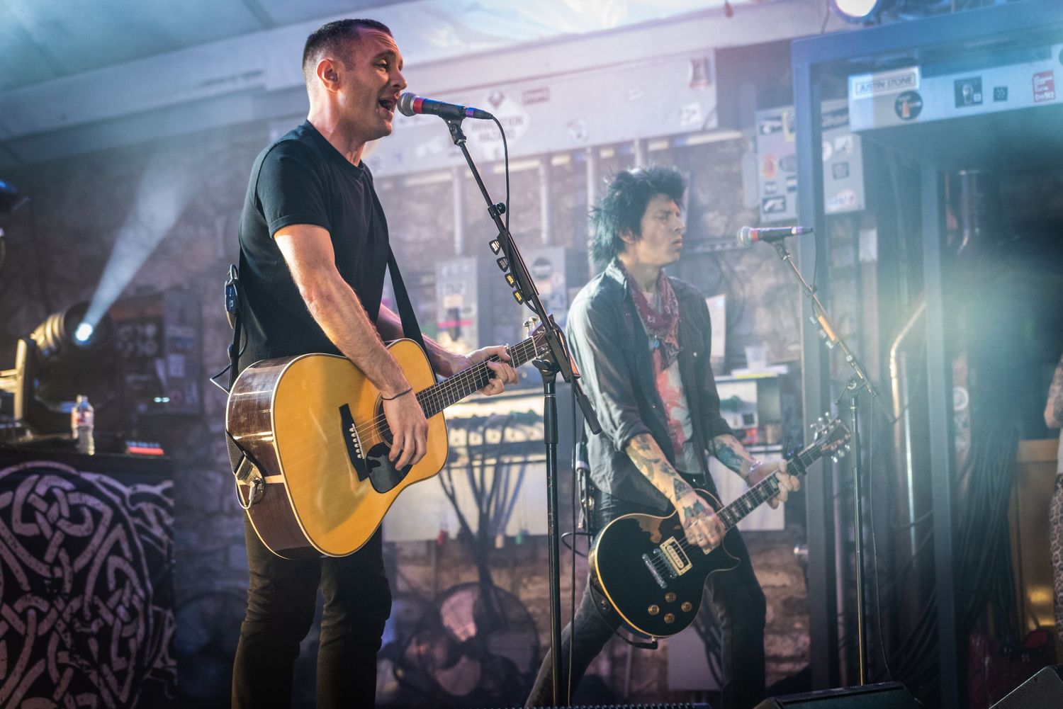 Musicians perform on stage with acoustic guitar and bass guitar during an energetic concert performance.