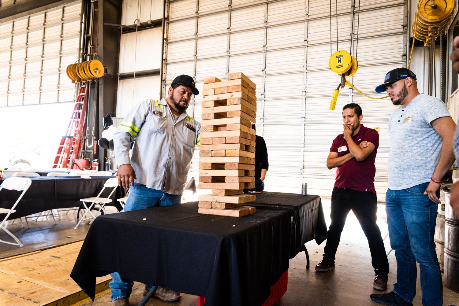 People playing giant Jenga game at indoor corporate event.