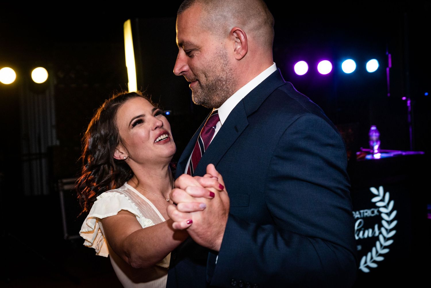 Couple sharing a romantic dance moment under evening reception lighting.