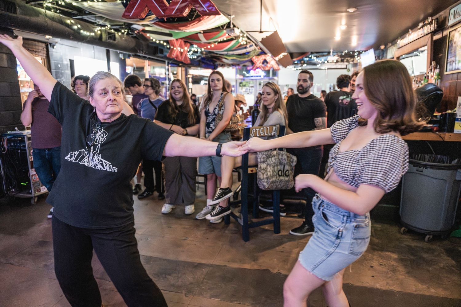 People dancing together at a crowded bar or pub with festive decorations visible in the background.