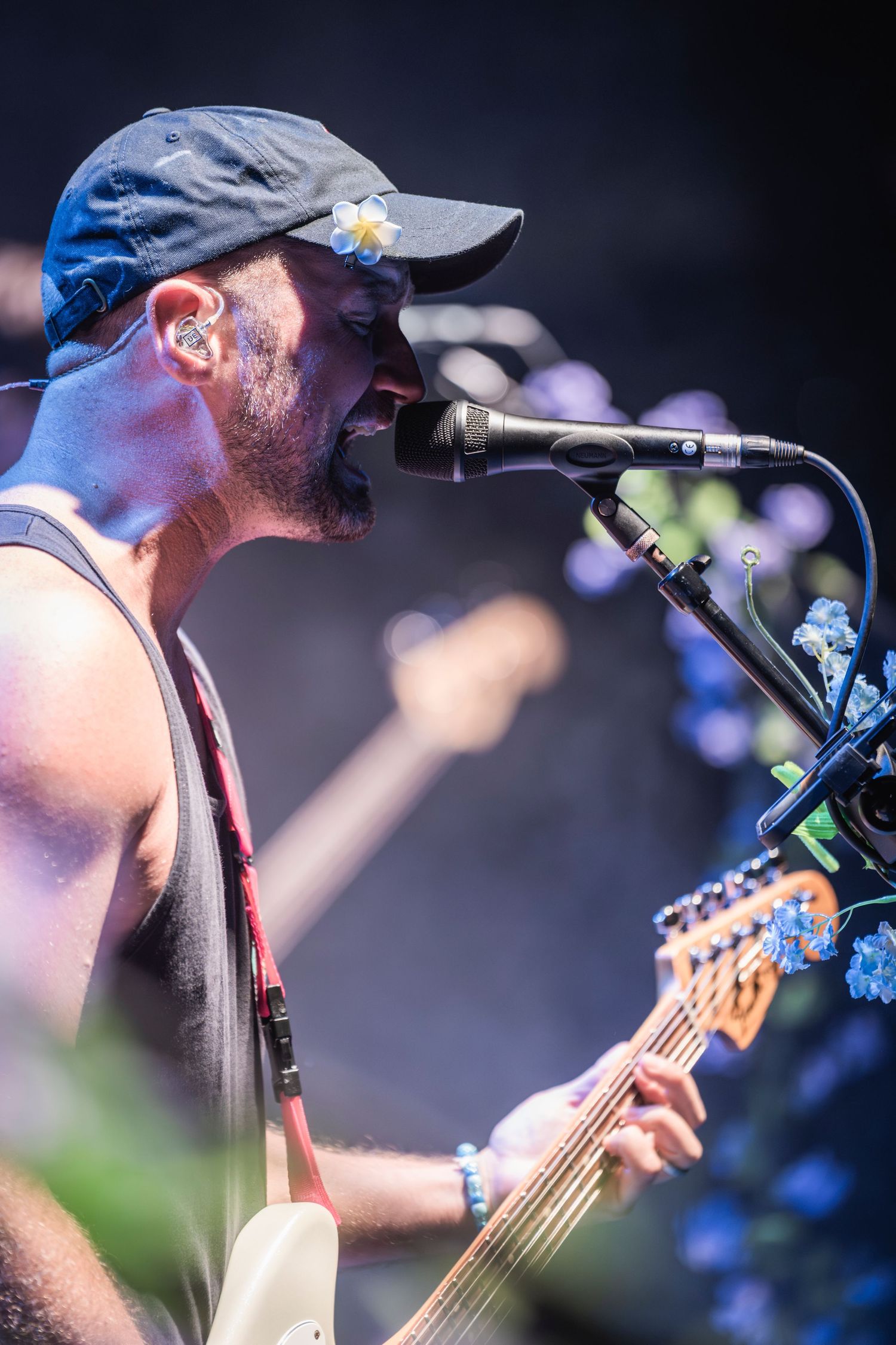 A musician performs on stage with a microphone and guitar during a live concert with blue lighting effects.
