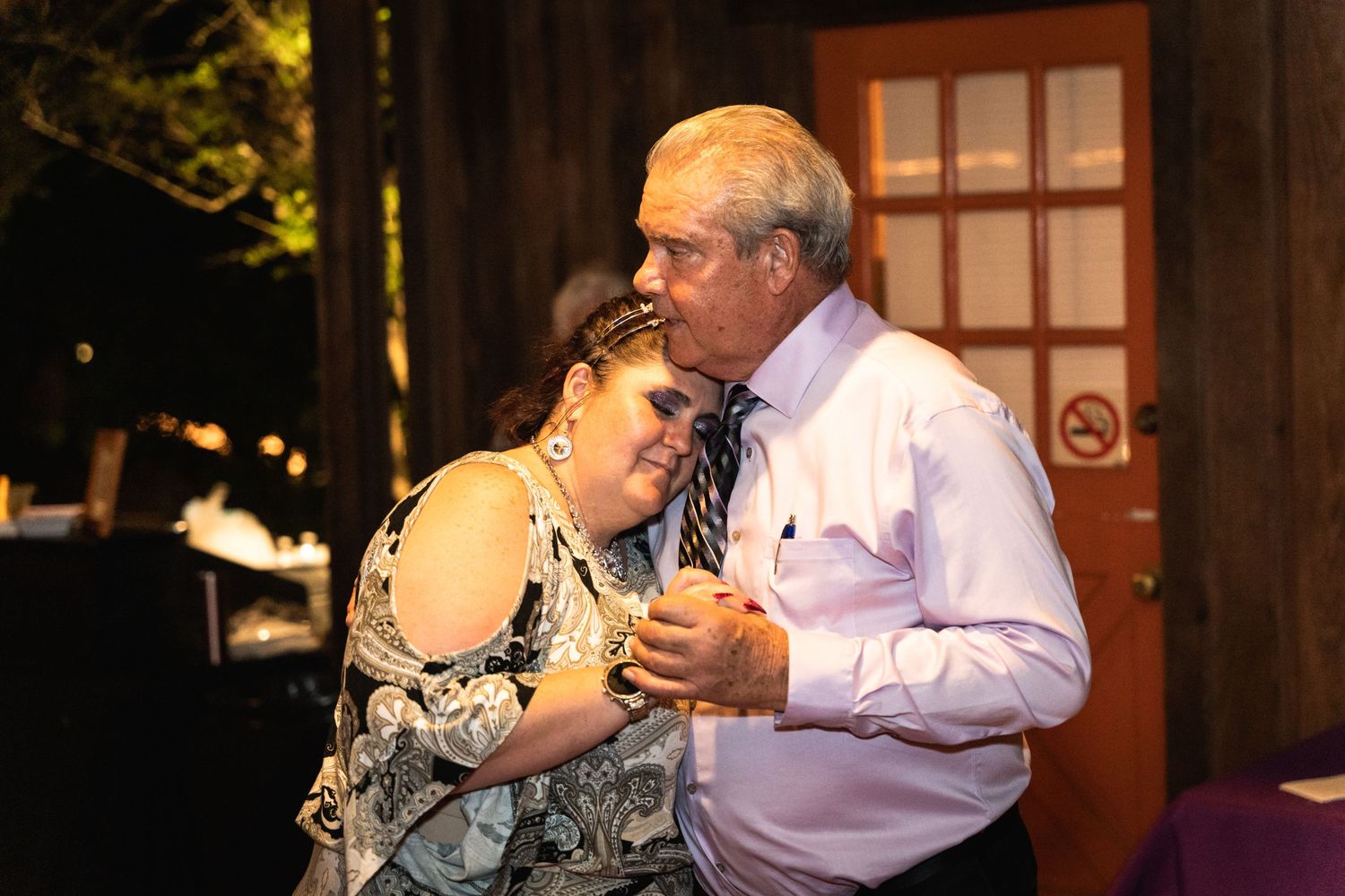 A tender slow dance moment between two people at an evening reception.