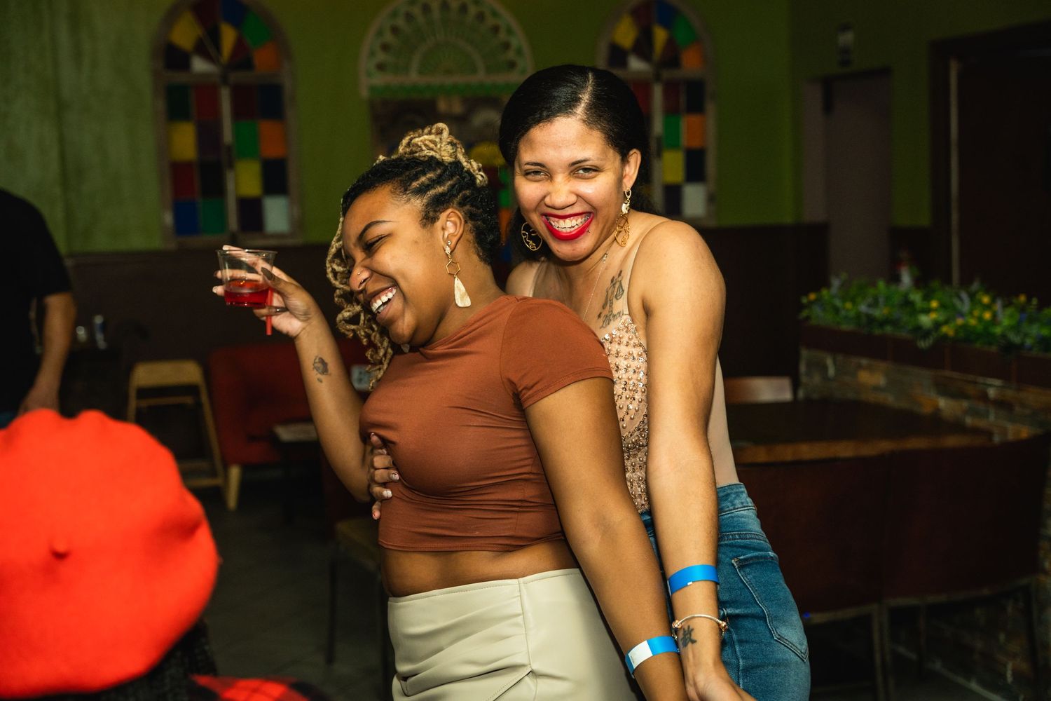 Friends laughing and dancing together at a party with colorful lighting.