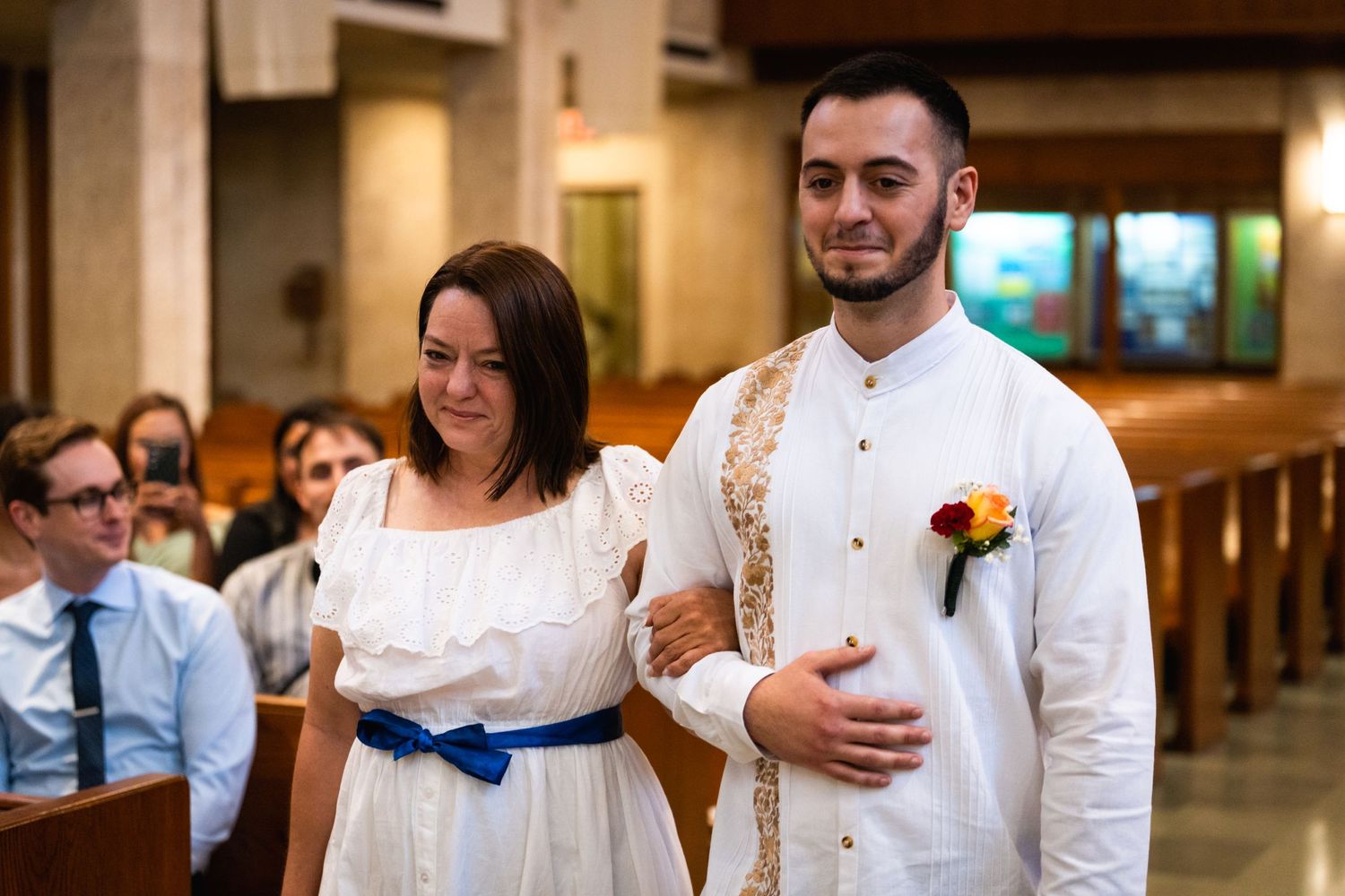 Couple in white attire walks down church aisle during traditional wedding ceremony.