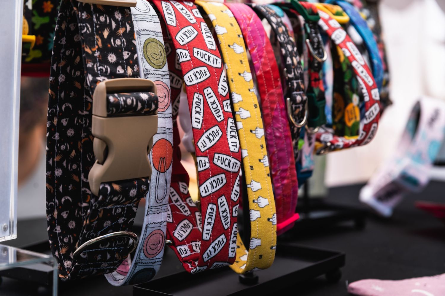 Colorful patterned dog collars with bandana designs displayed on retail rack.