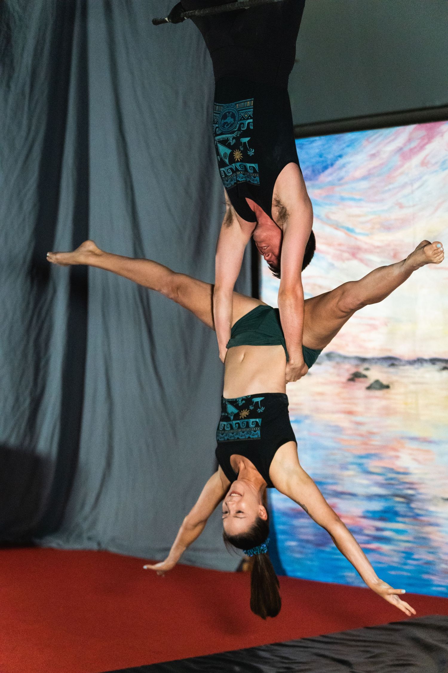 Two aerial artists perform an impressive inverted duet against painted backdrop.