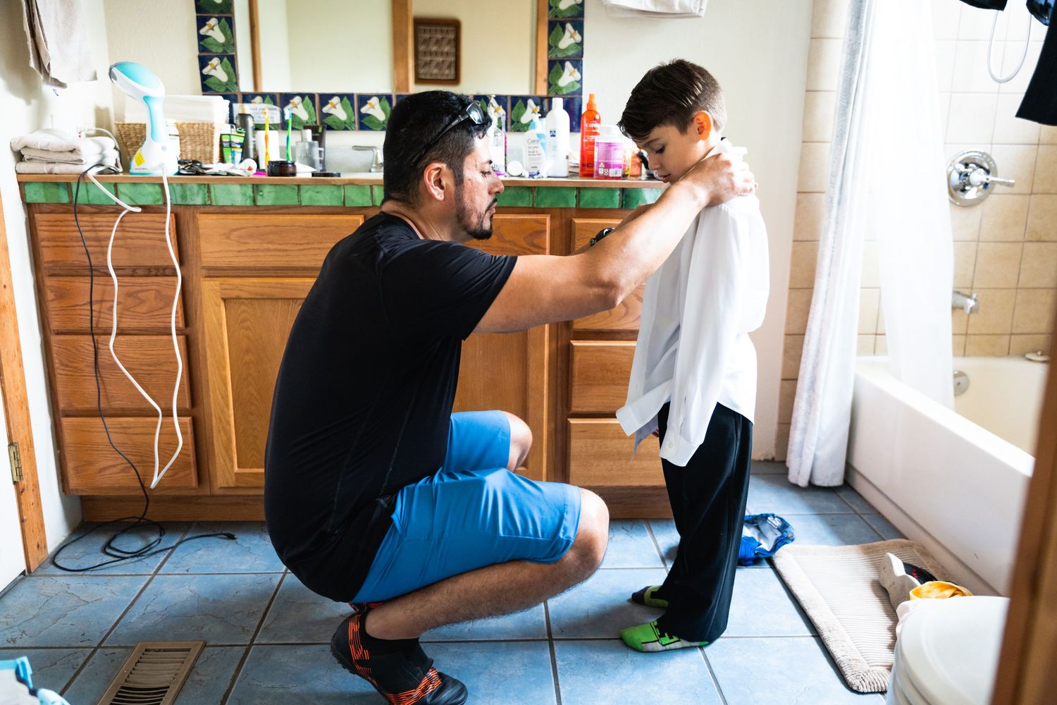 Adult helping child get ready in a kitchen setting.
