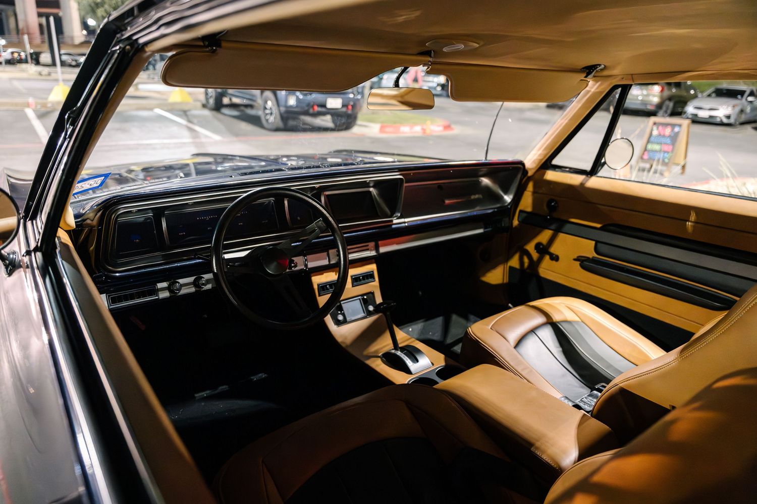 Interior view of a classic car showing vintage dashboard and tan leather seats.