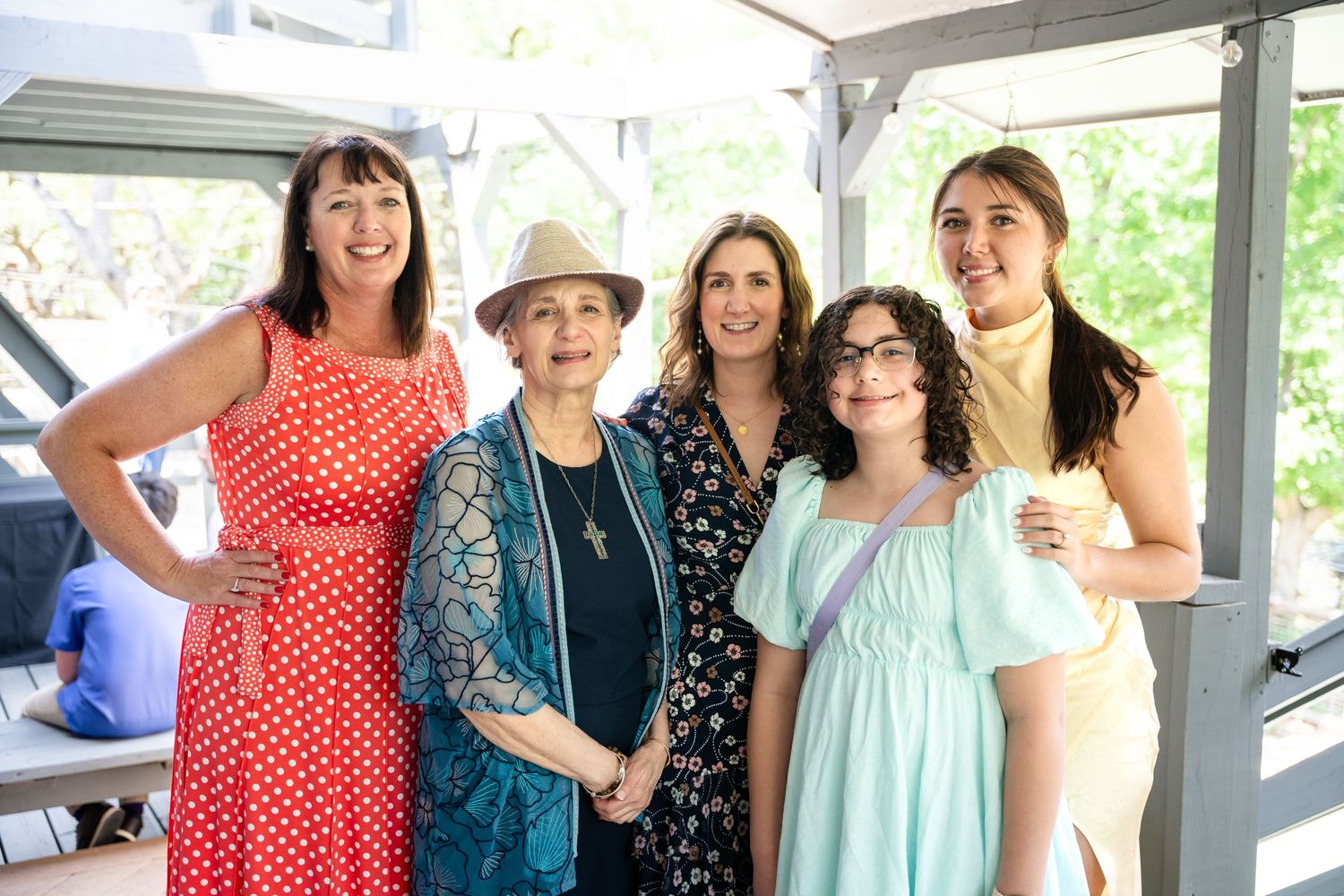 Group wearing colorful sundresses and casual attire gathered under covered outdoor area.