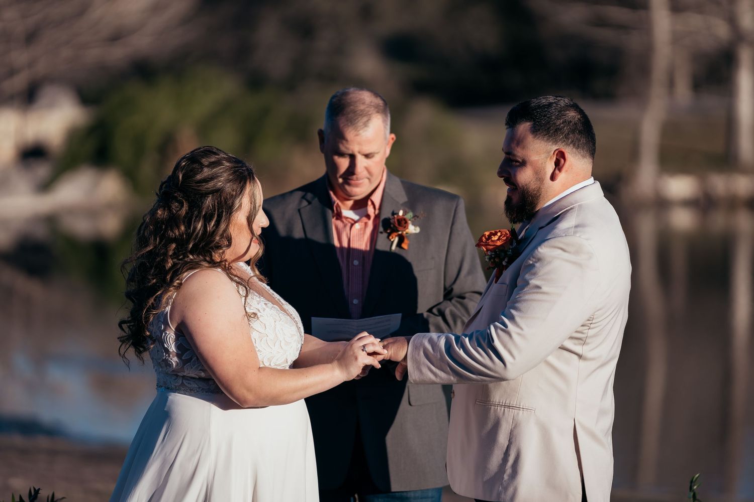Exchange of rings during waterfront wedding ceremony with officiant.