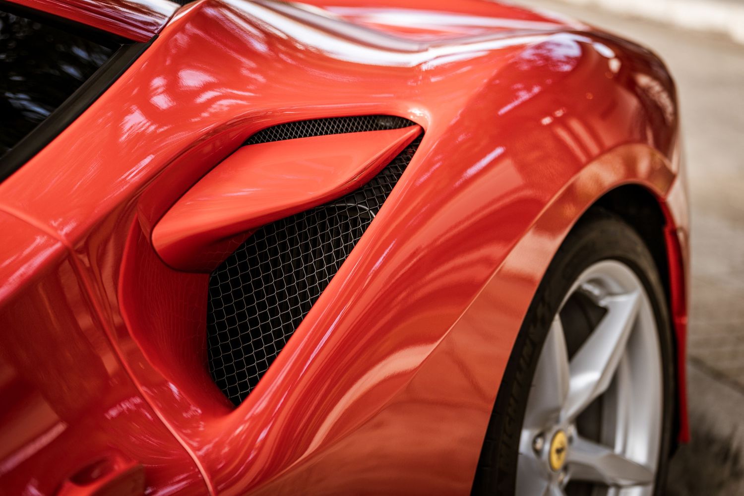 Detail shot of a red Ferrari's side air intake and sculpted body panel.