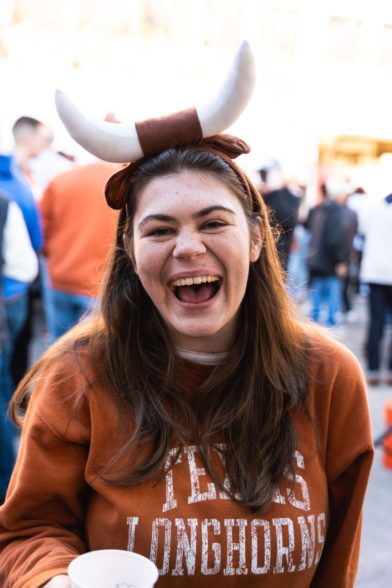 Fan wearing Longhorns sweatshirt and decorative horns headband at sporting event.