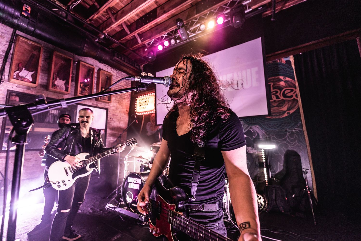 Rock concert performer singing passionately on stage with dramatic purple lighting.