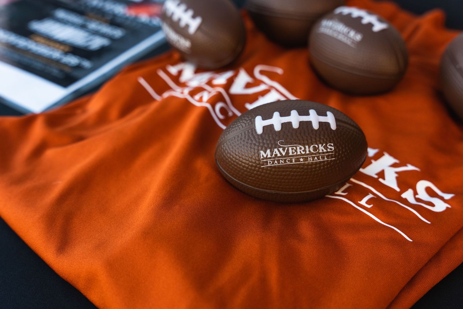 Orange t-shirt and mini footballs with Mavericks Dance Hall branding displayed.
