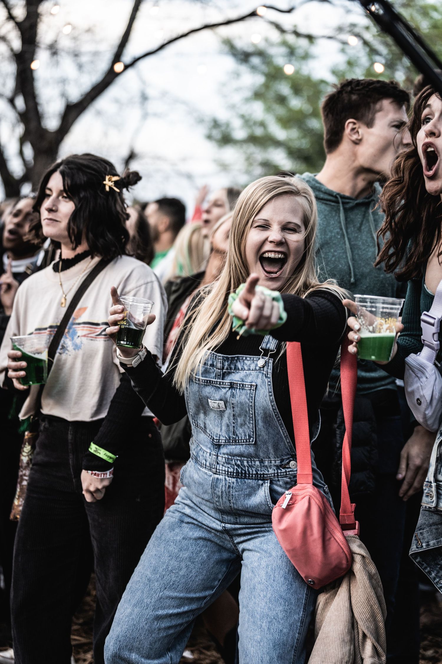 Joyful crowd members in denim and casual wear enjoying an outdoor festival atmosphere.