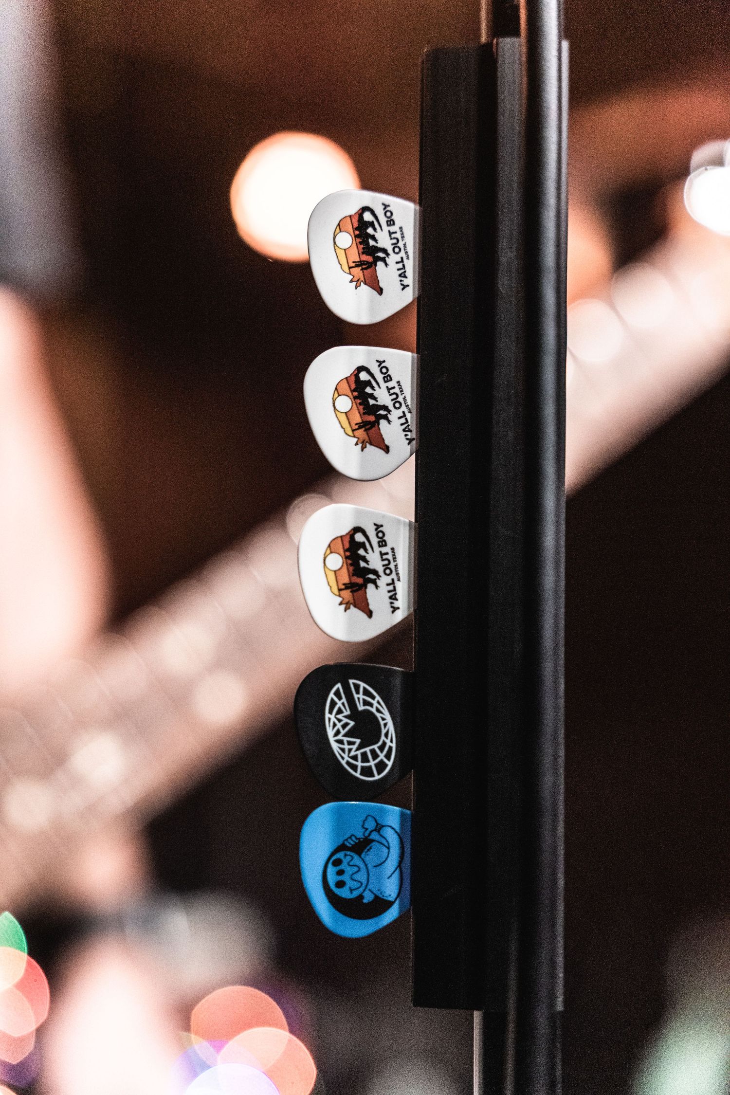 Collection of guitar picks with band logos displayed on a stand.