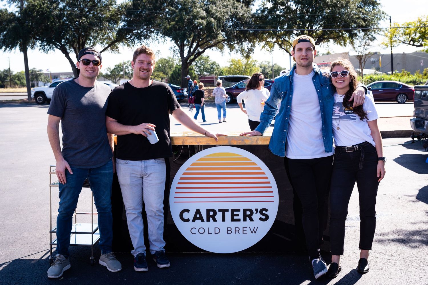 Group photo of team members behind Carter's Cold Brew branded display at outdoor event.