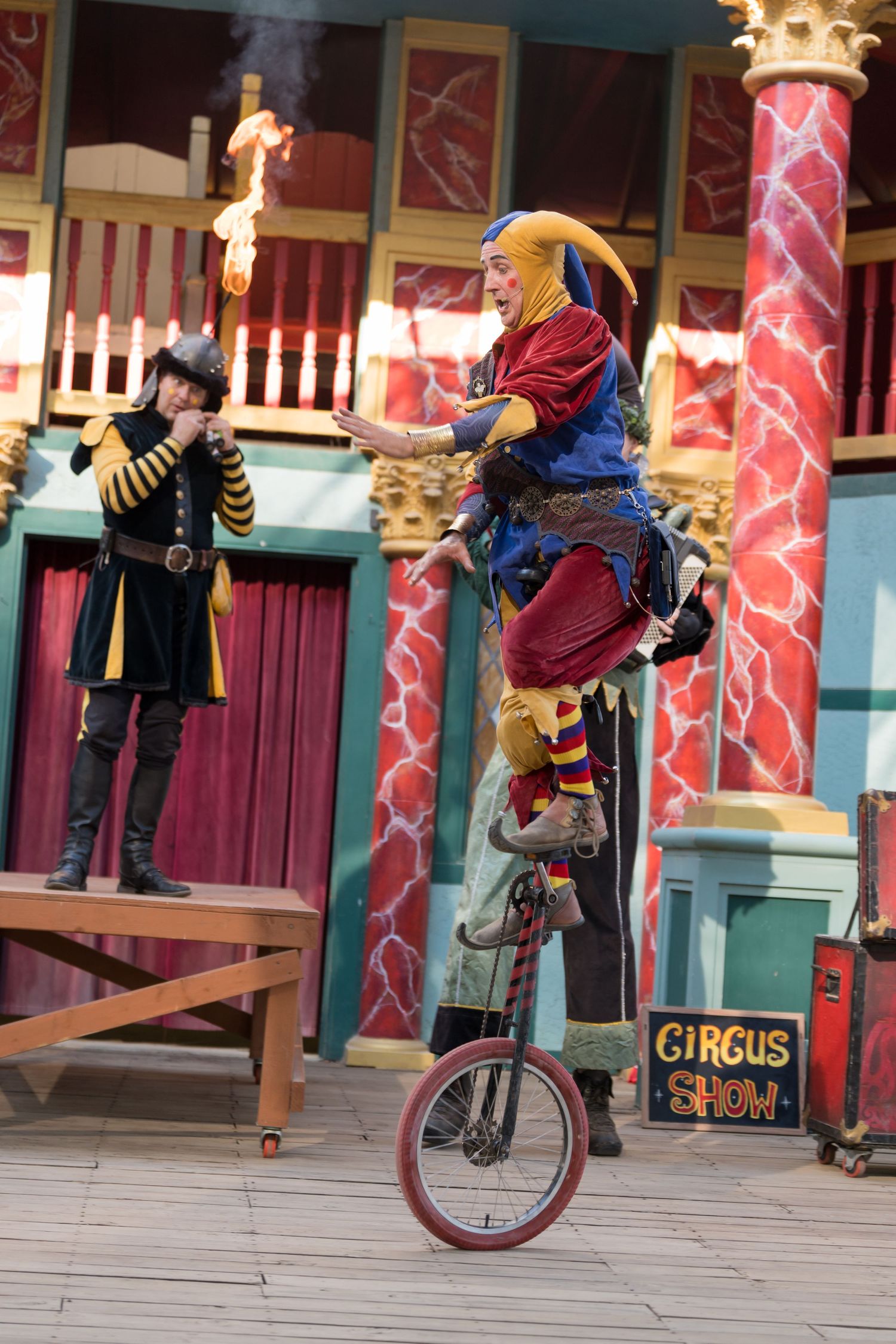 Circus performer balancing on a unicycle during a theatrical show.