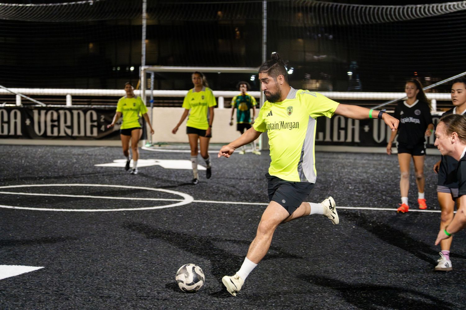 Soccer player in neon yellow uniform prepares to kick the ball during an indoor match.