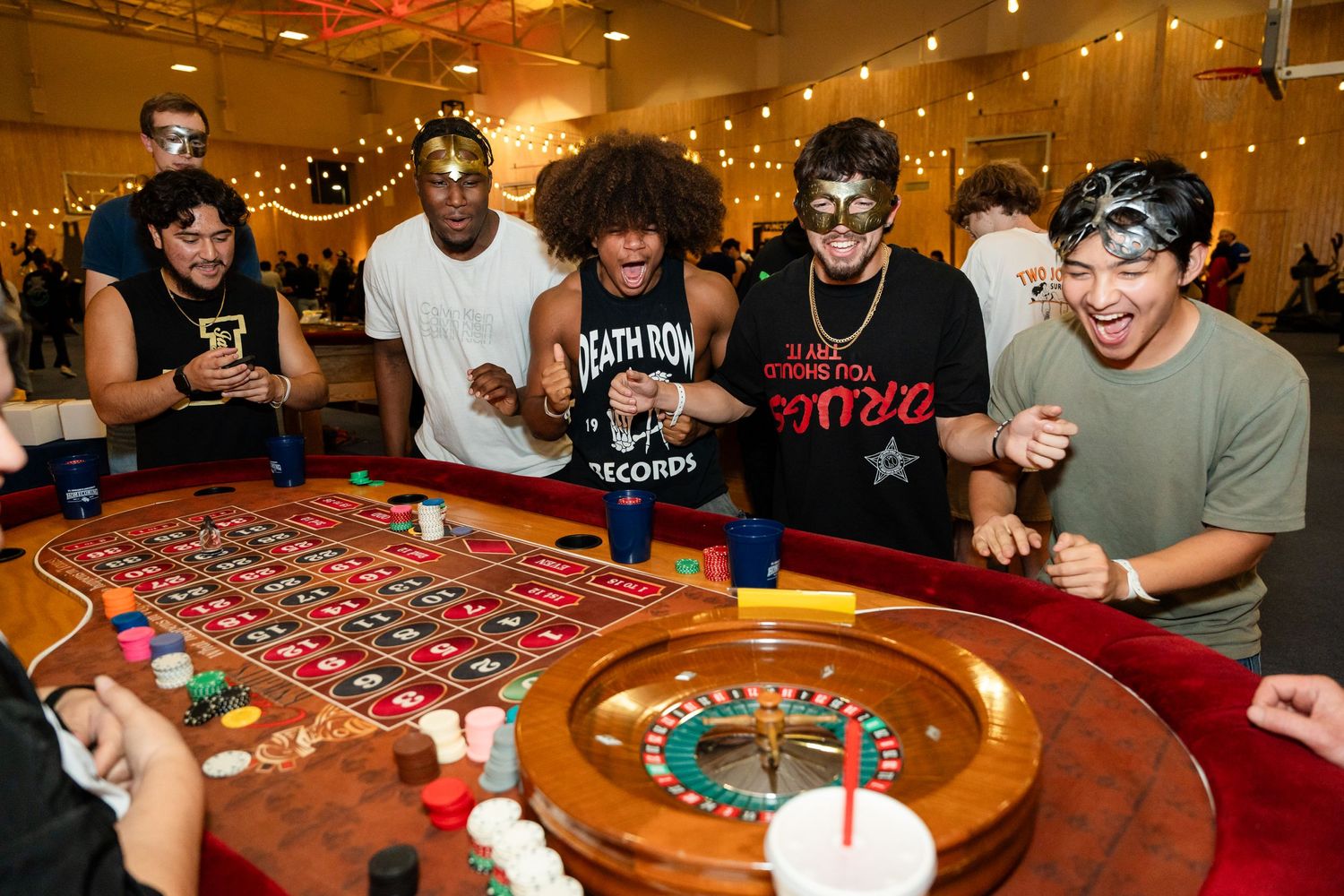 Players excitedly watch the roulette wheel spin during a casino gaming event.