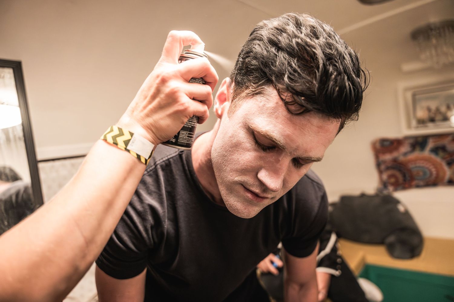 Person applying hair product or styling their hair in dimly lit room.