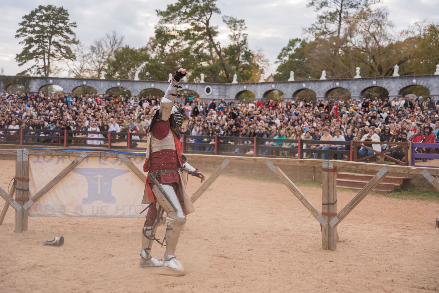 A medieval warrior performs before a packed amphitheater at a renaissance festival.