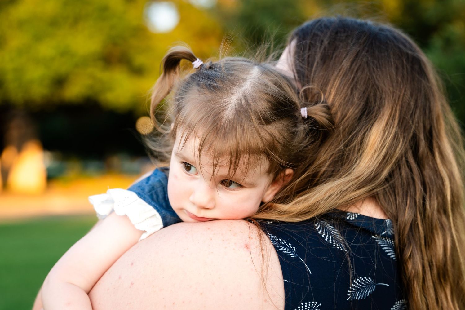 An intimate embrace captured in warm evening sunlight with bokeh effects in the background.