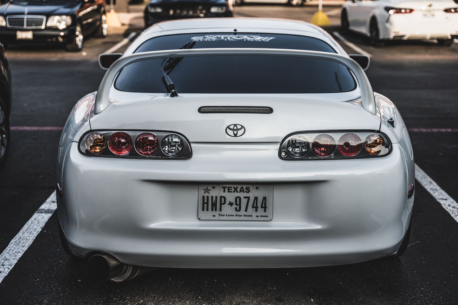 Rear view of a silver Toyota Supra showing custom taillights and license plate.