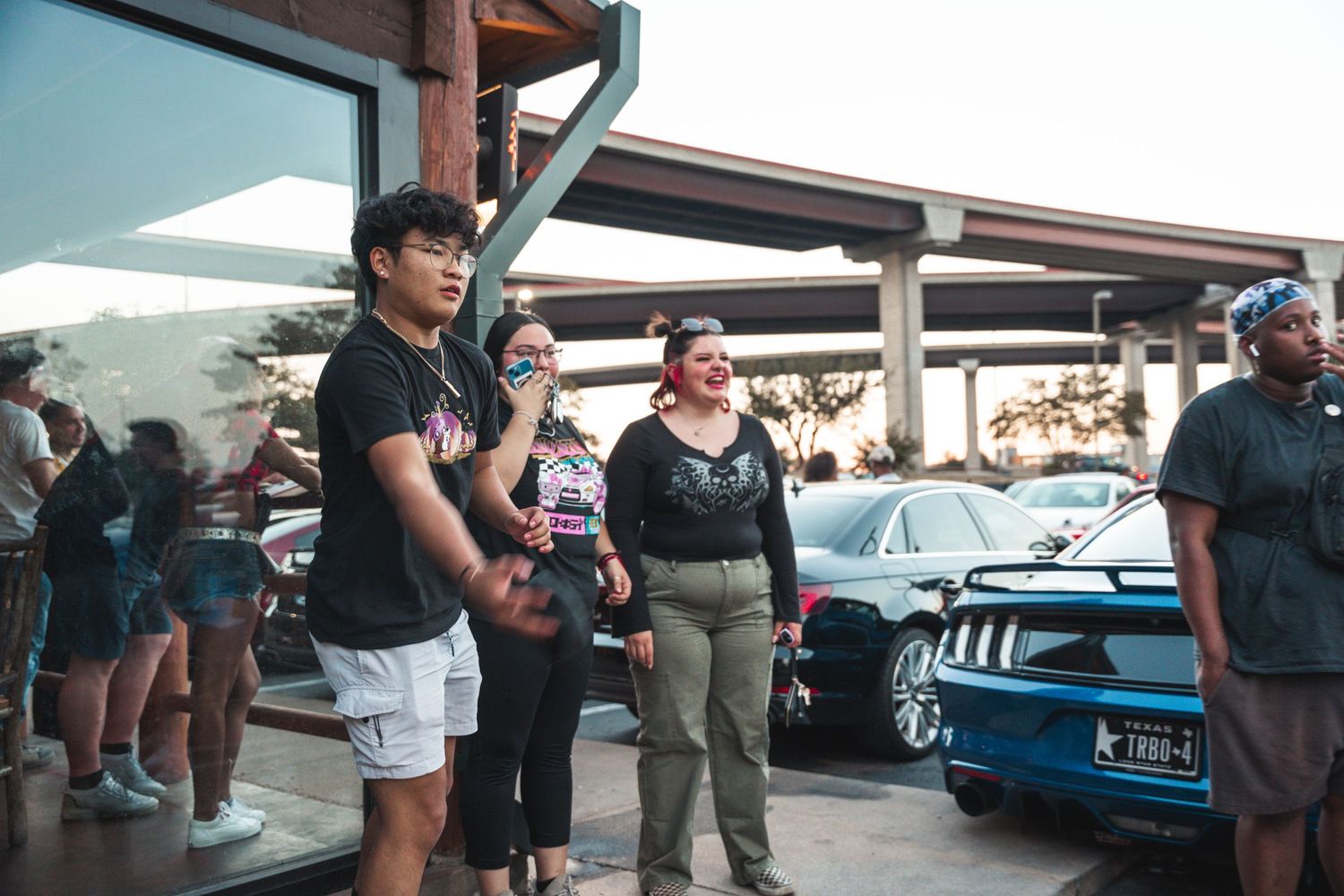 Car enthusiasts gathered at outdoor automotive meet during sunset.