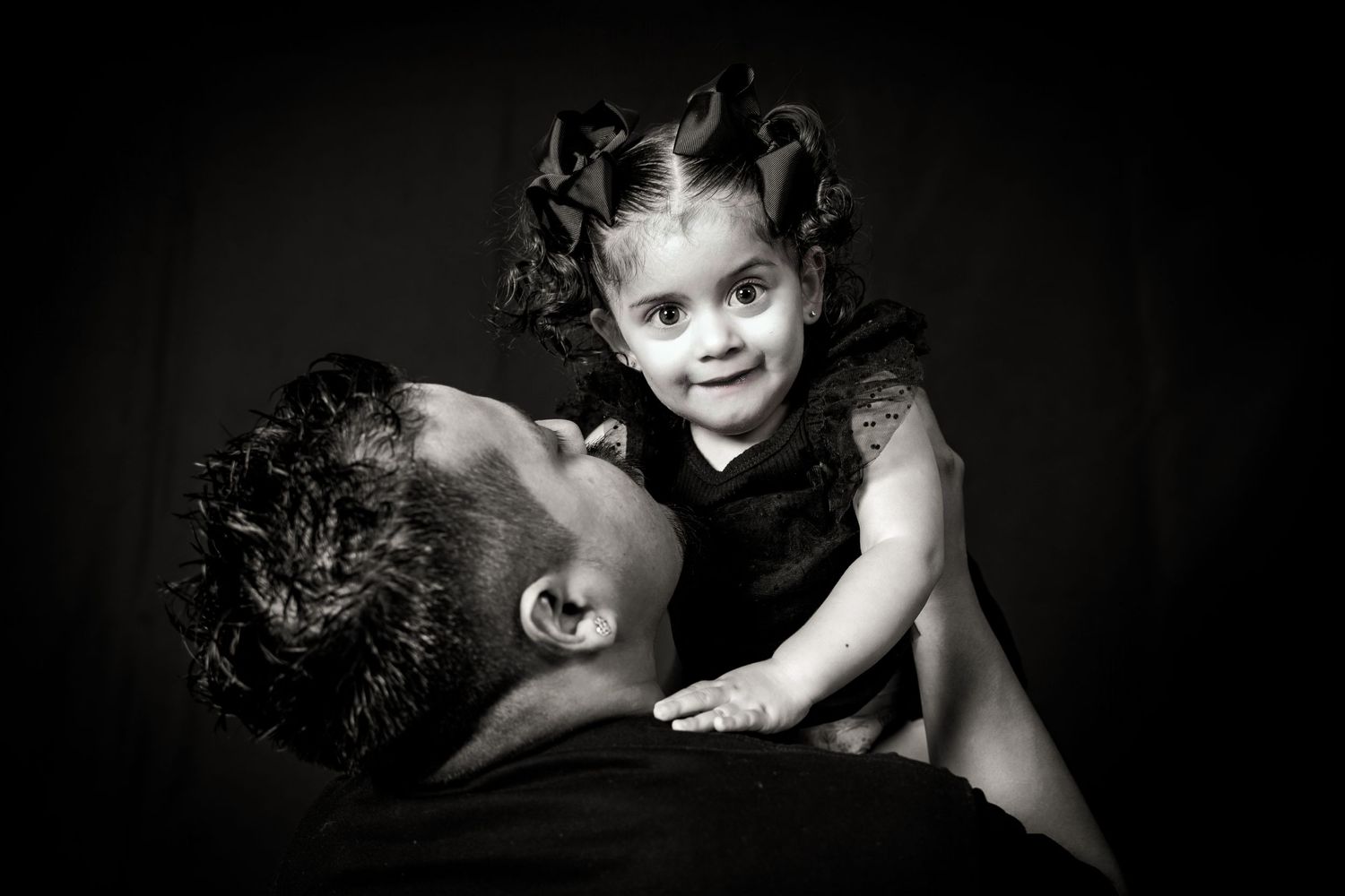 Intimate black and white photograph capturing joyful interaction between parent and child.