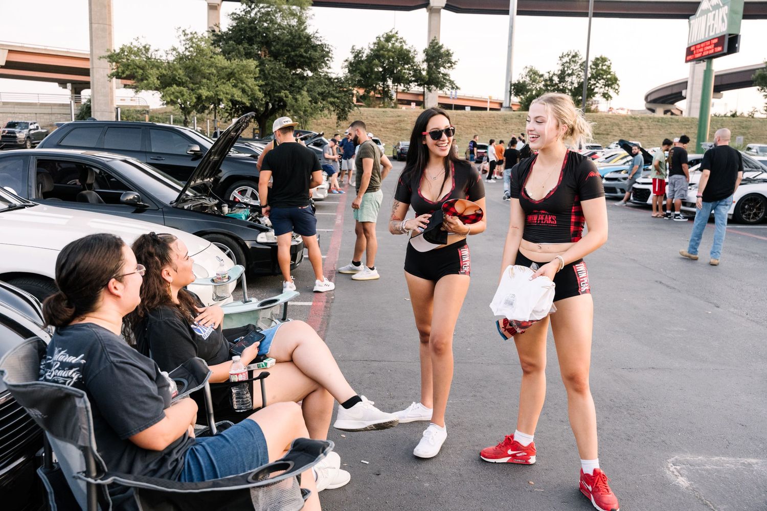 Group of attendees socializing at an outdoor car meet event.