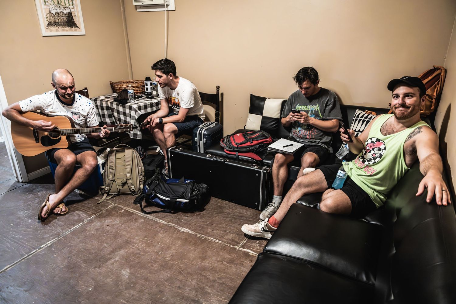 Musicians rehearsing together in a casual studio space with guitars and equipment.
