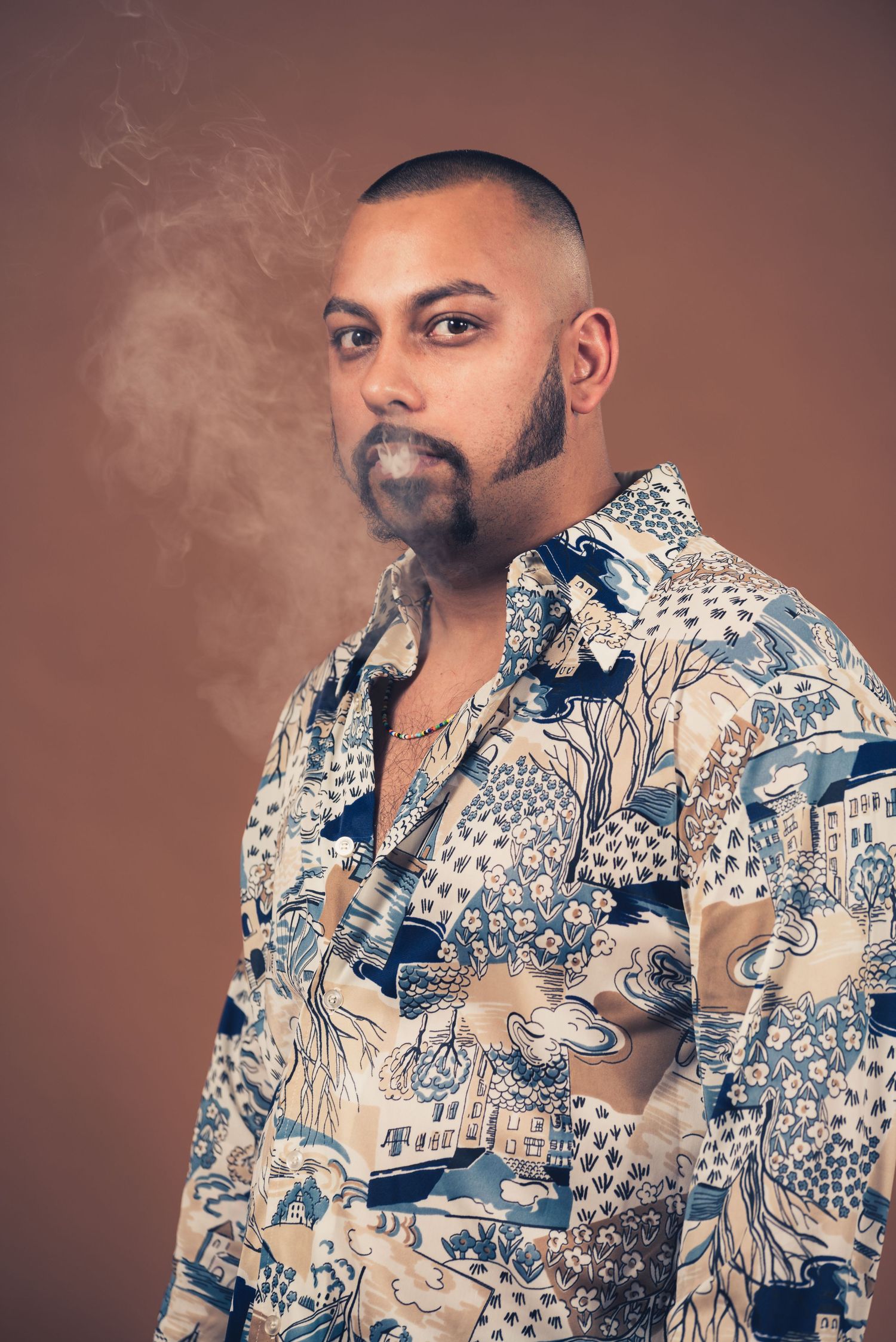 Portrait of person in patterned shirt with smoke effect against brown background.