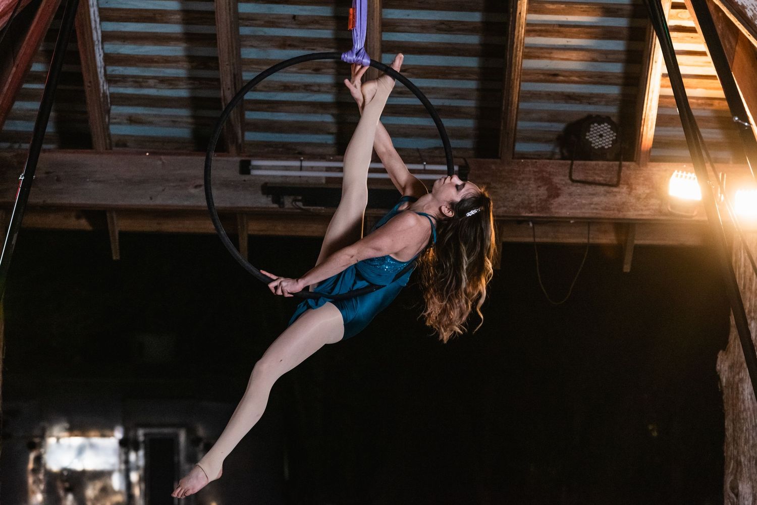 Aerial hoop performance in dimly lit industrial space.