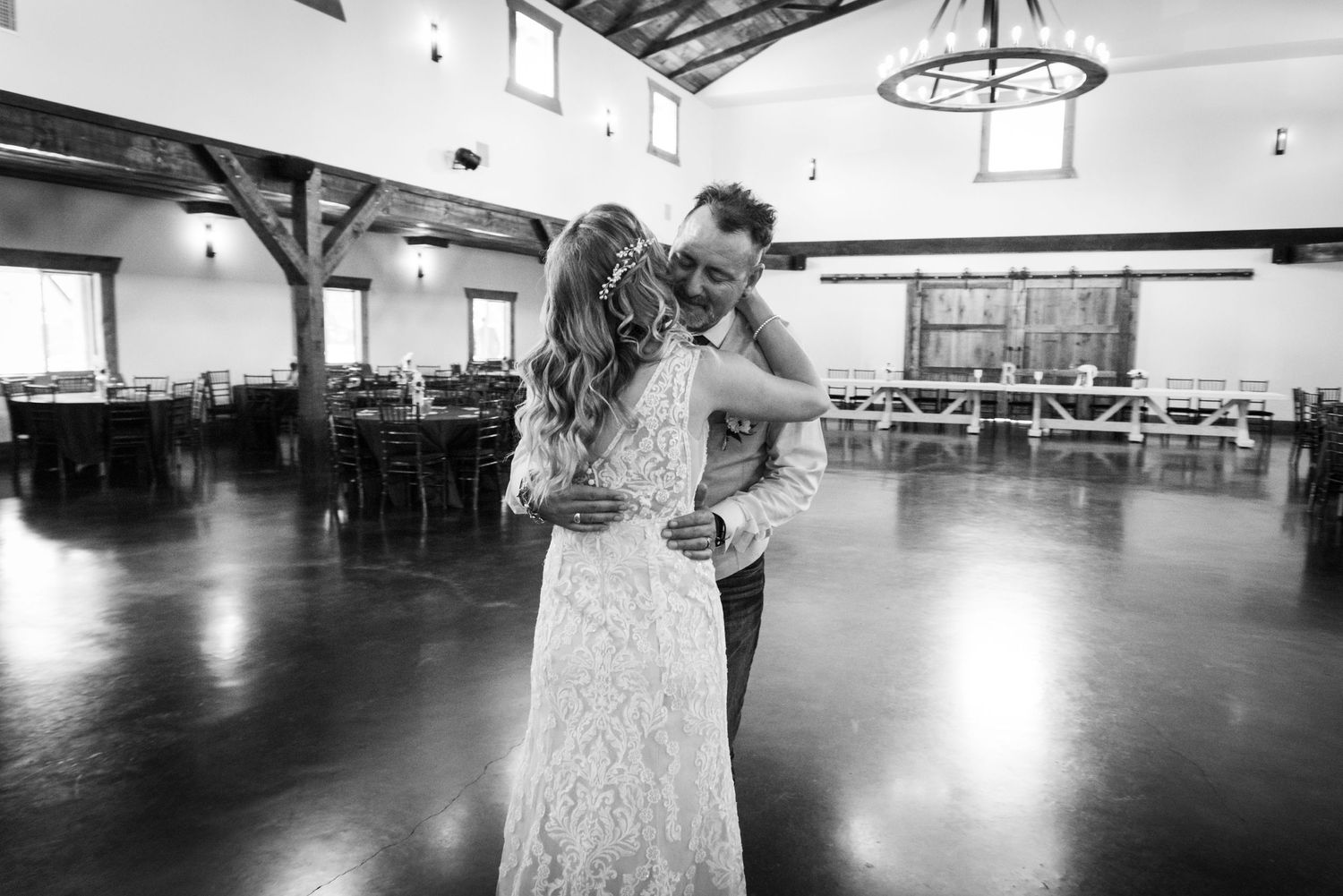 A romantic black and white dance moment captured in a spacious reception hall with elegant lighting.
