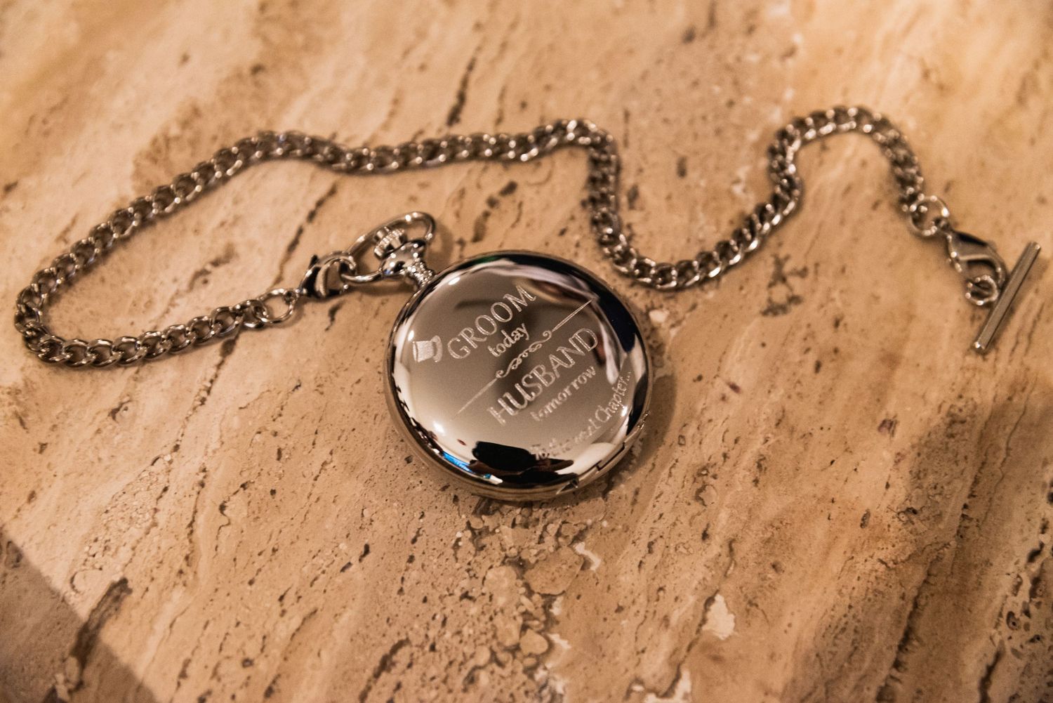 A vintage pocket watch with chain rests on a wooden surface.