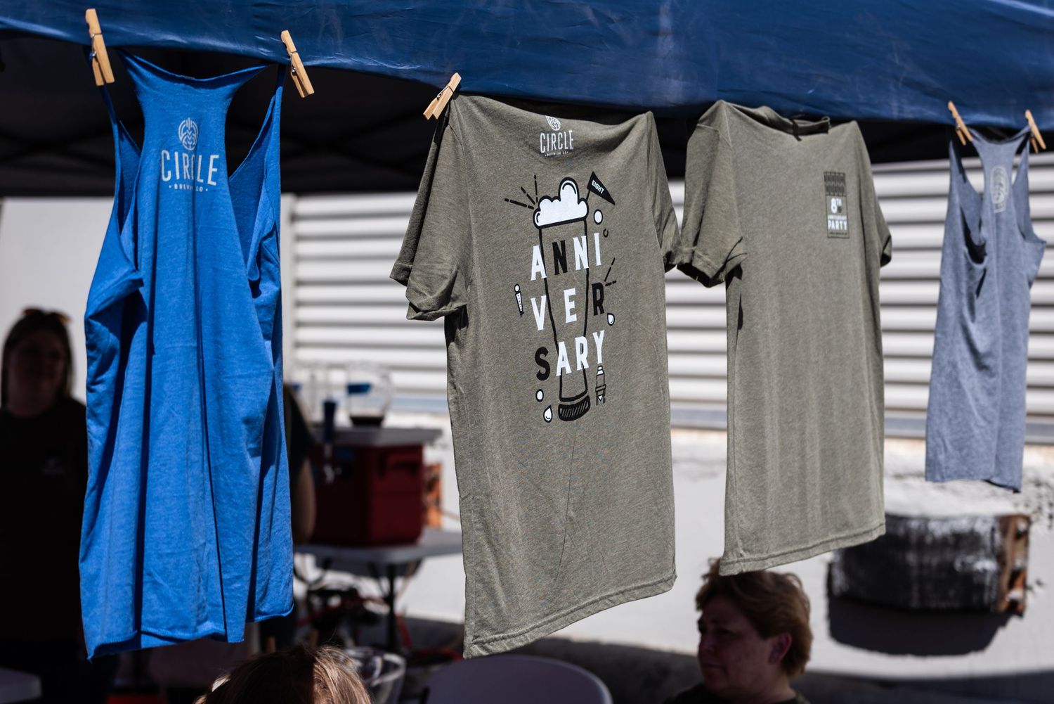 T-shirts and merchandise displayed on clothesline at outdoor vendor booth.