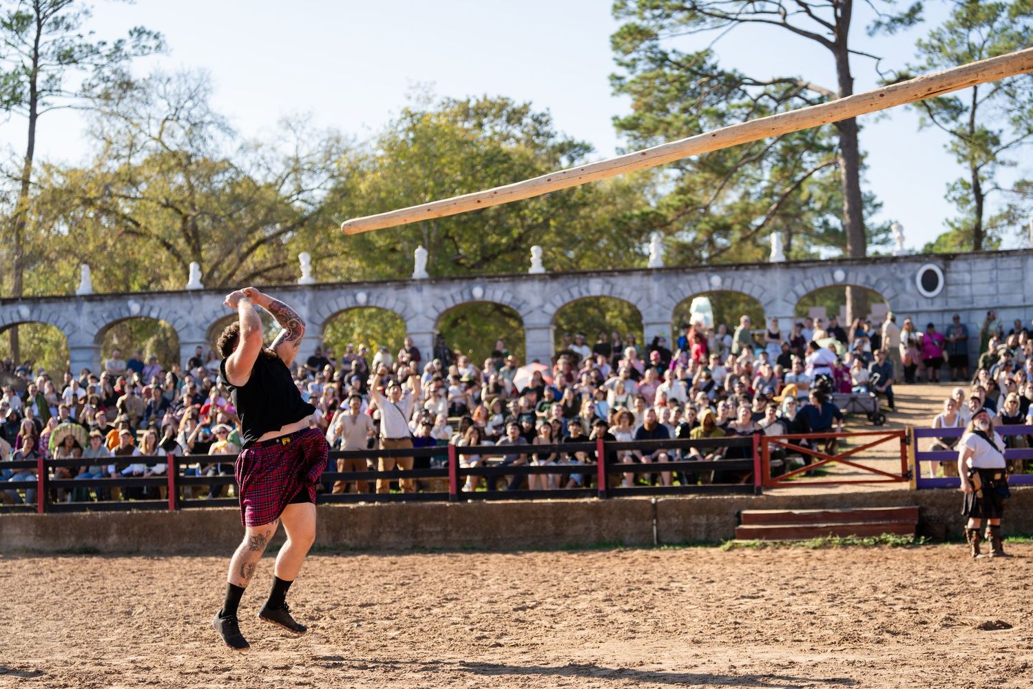 Students gather outdoors to watch a competitive tug-of-war match on a sunny day at a school field.