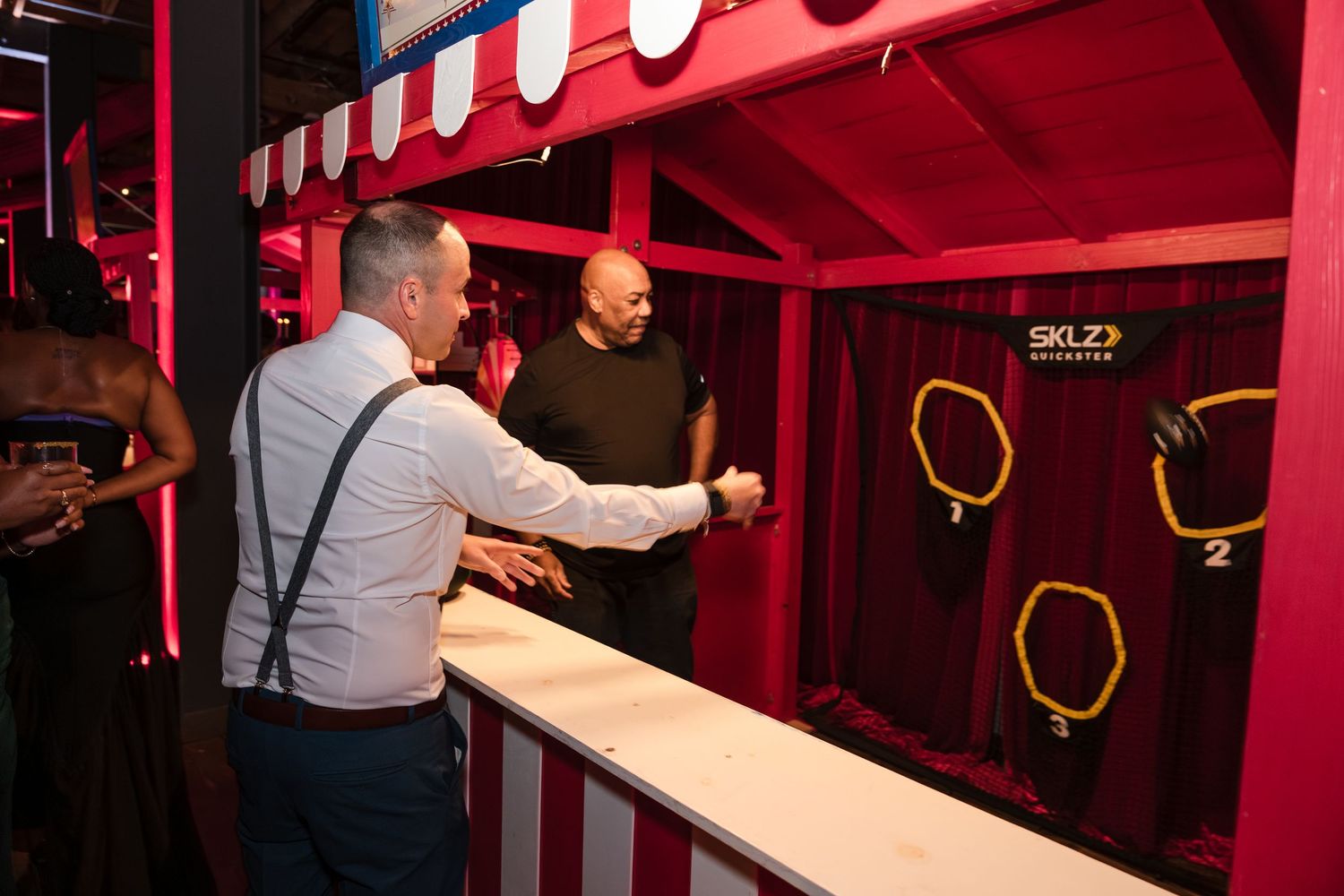 A person works on installing a long wooden beam in a red-lit entertainment or theater space.