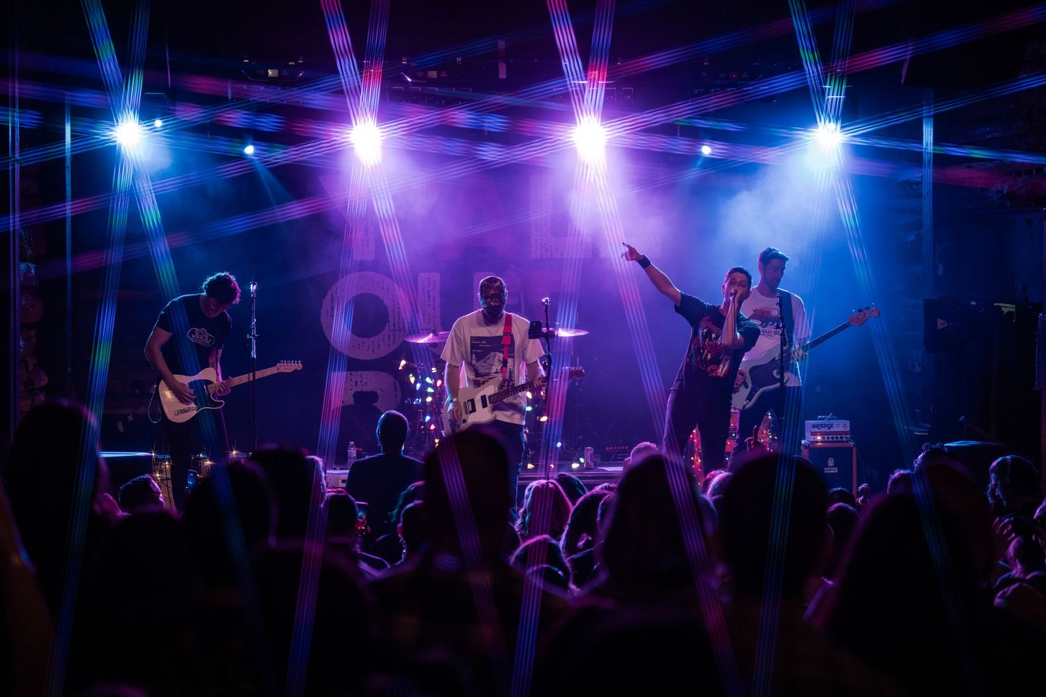 Concert stage illuminated with vibrant blue and purple lighting during a live music performance.