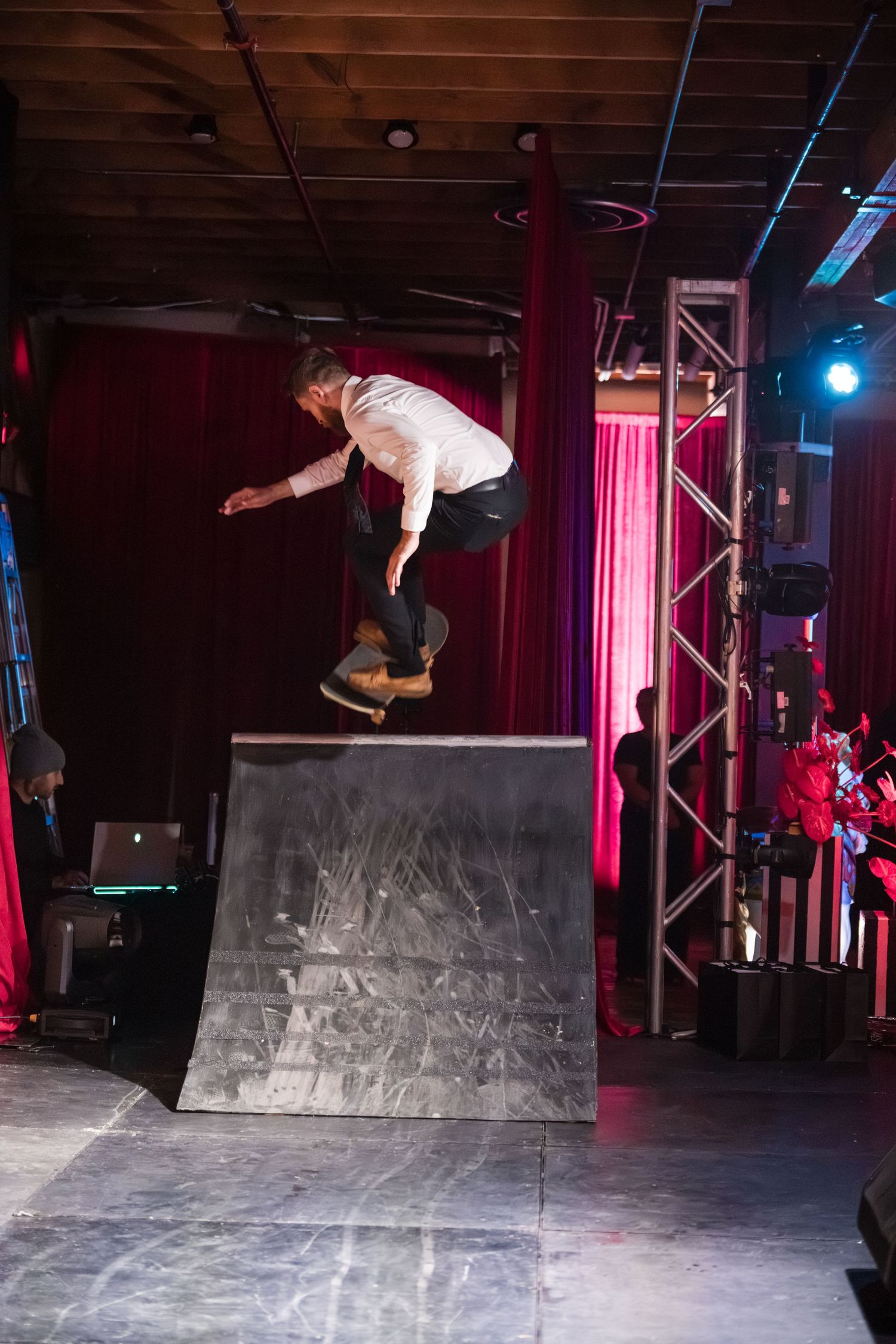 A skateboarder performs a sequence of tricks on a curved ramp in a dimly lit indoor skate park with red lighting.