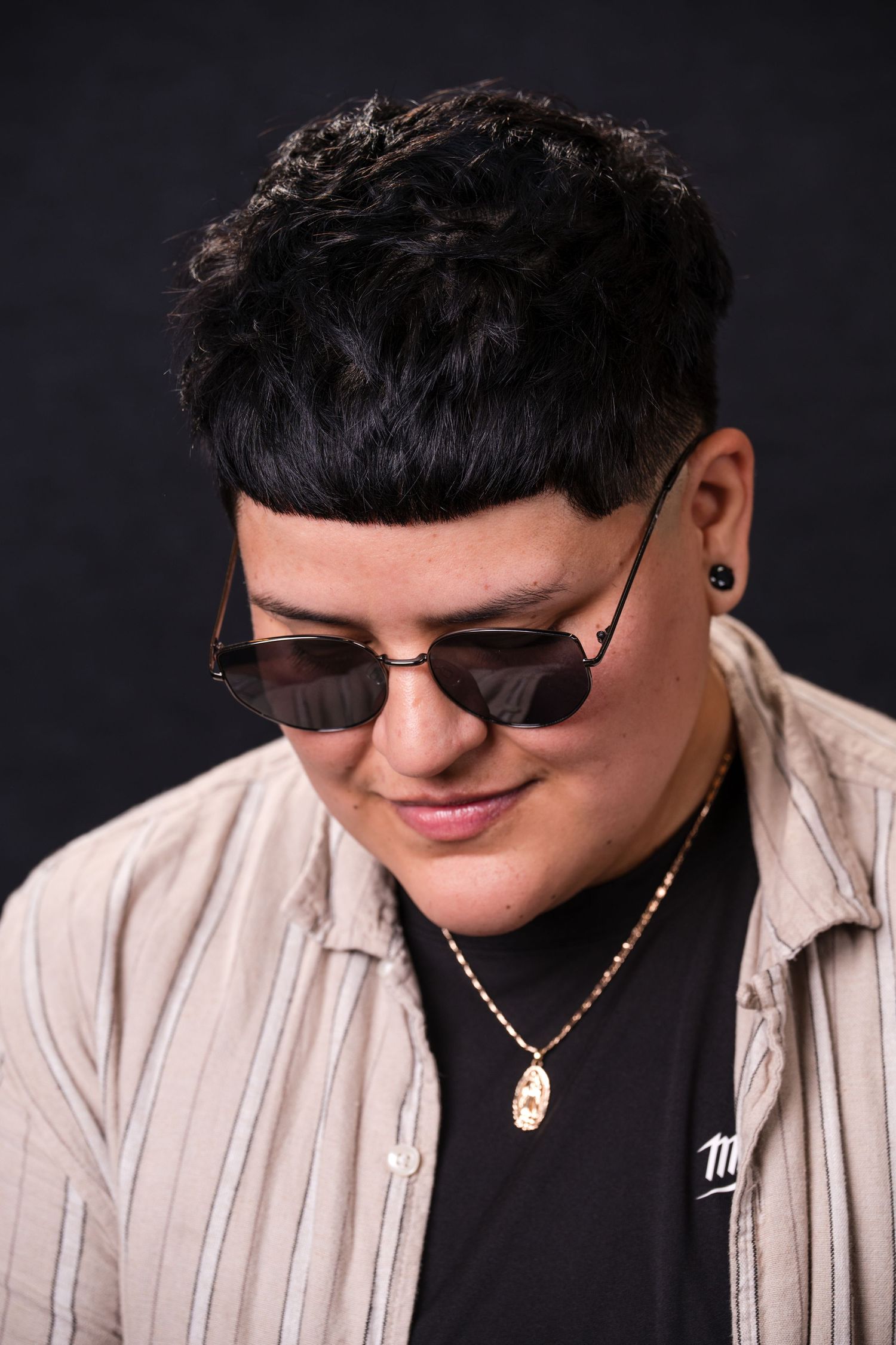 A person wearing sunglasses and a light colored shirt poses against a dark background in a series of close-up shots.